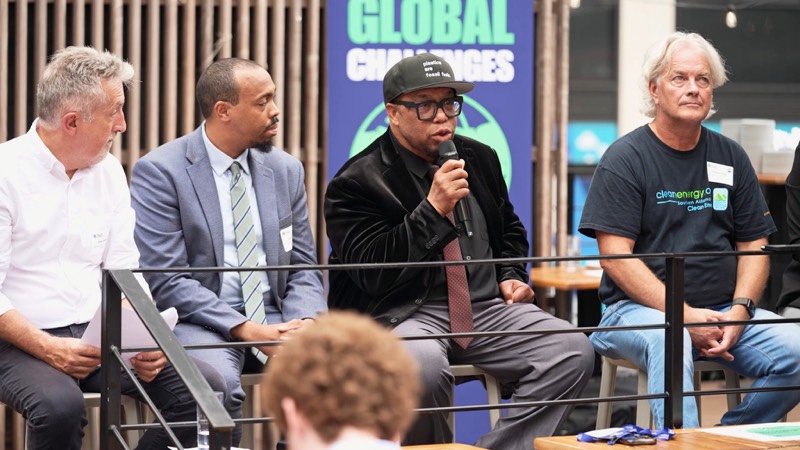 Four panelists seated in a row, one speaking into a microphone