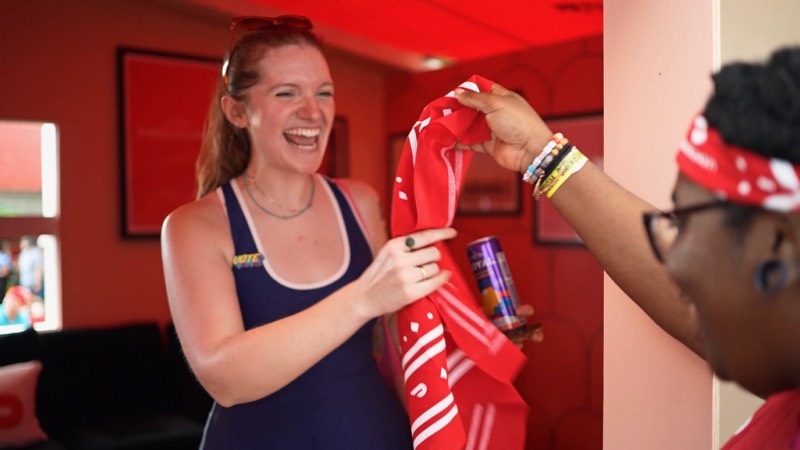 Two guests laughing at a brand event, one holding a red jersey